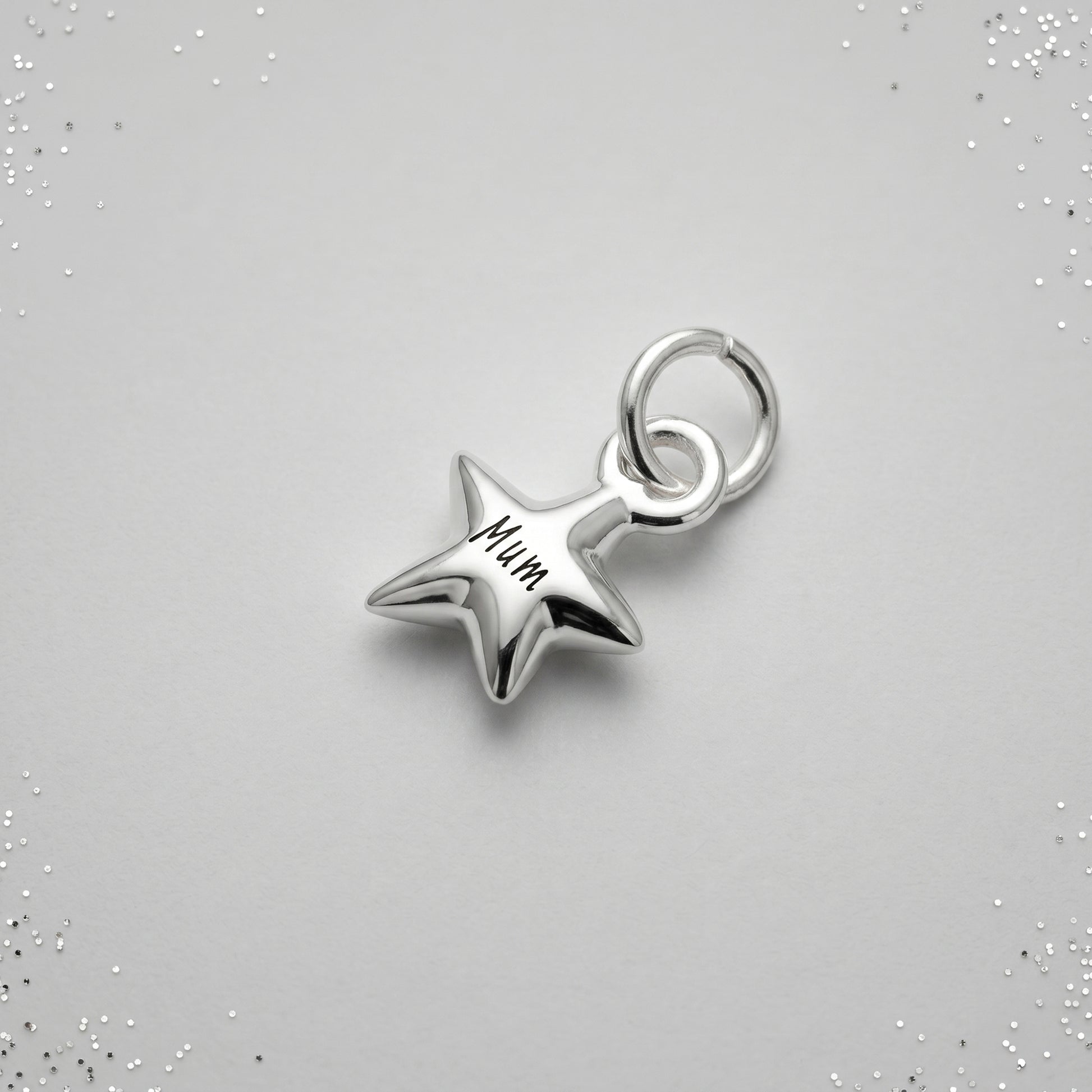 Silver star-shaped pendant with 'Mum' engraving on a gray background