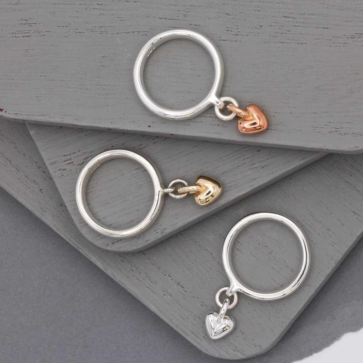 silver charm ring with dangling heart in silver, rose and gold hearts