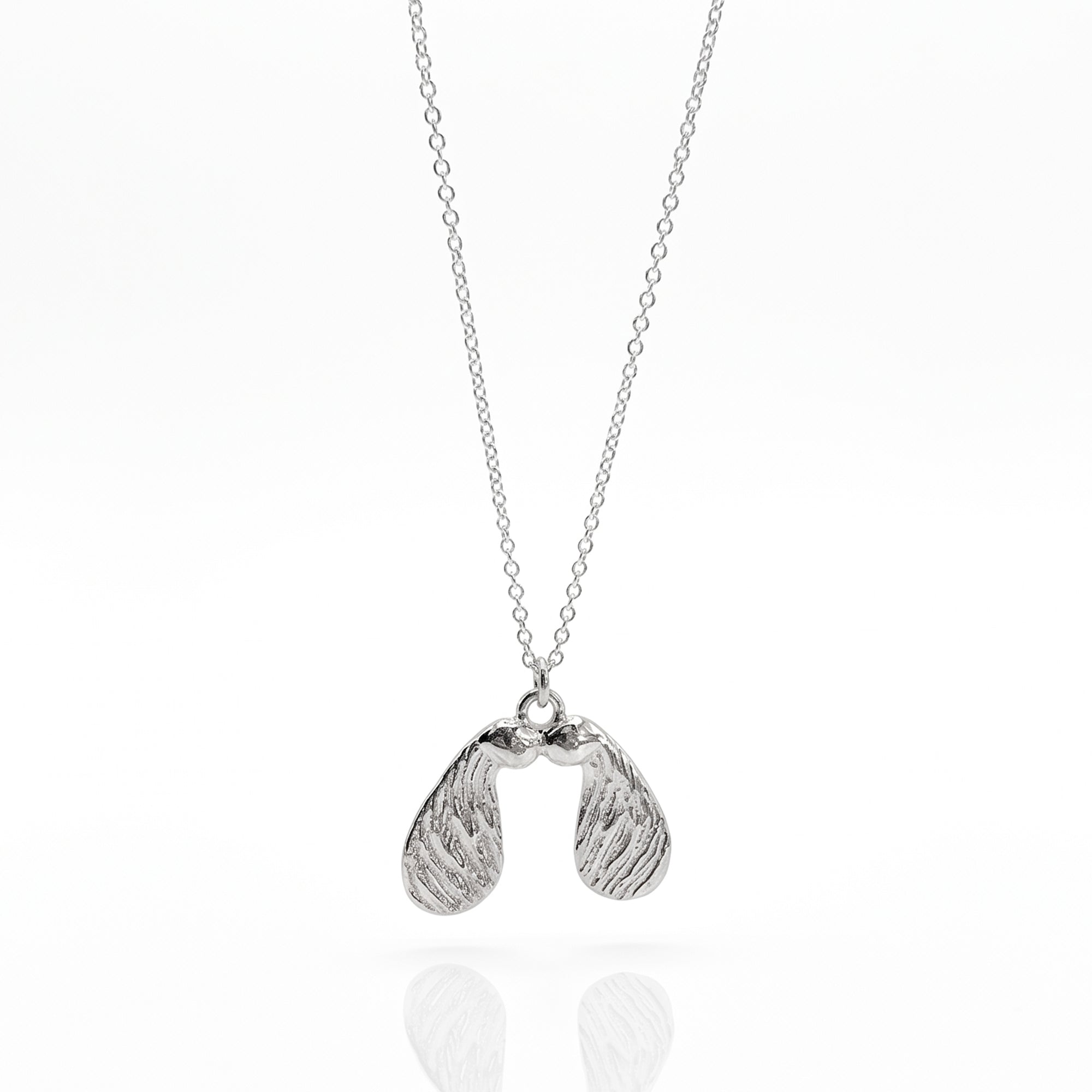 Silver necklace with a sycamore seed pendant on a white background