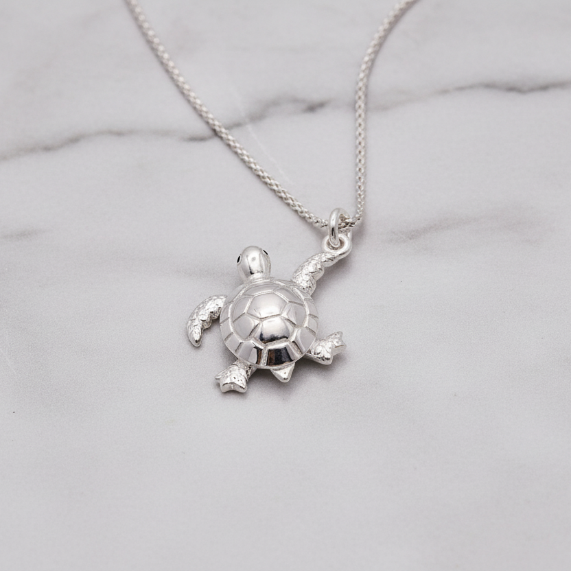 silver turtle necklace on marble background