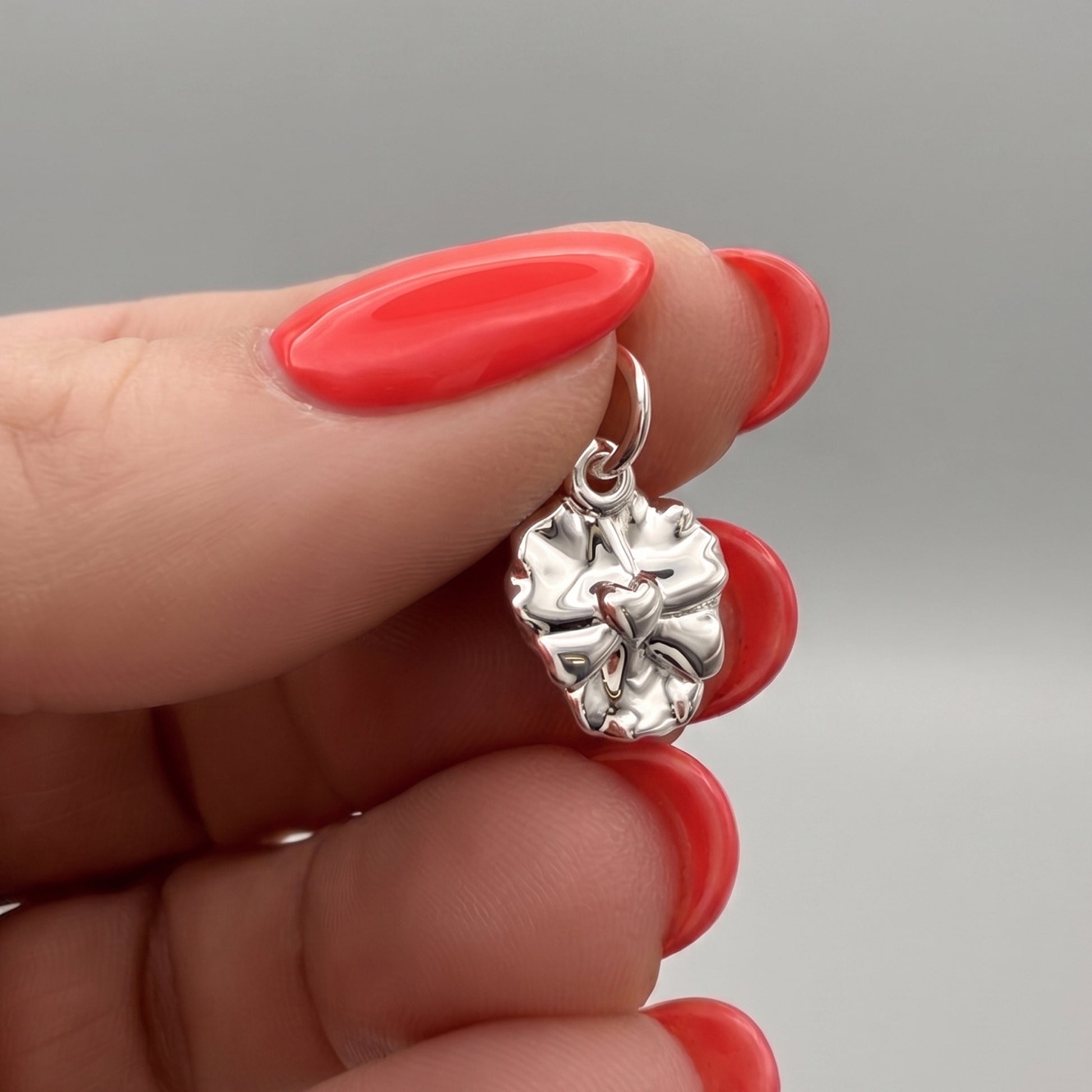 silver violet pansy flower charm on hands with red nail polish