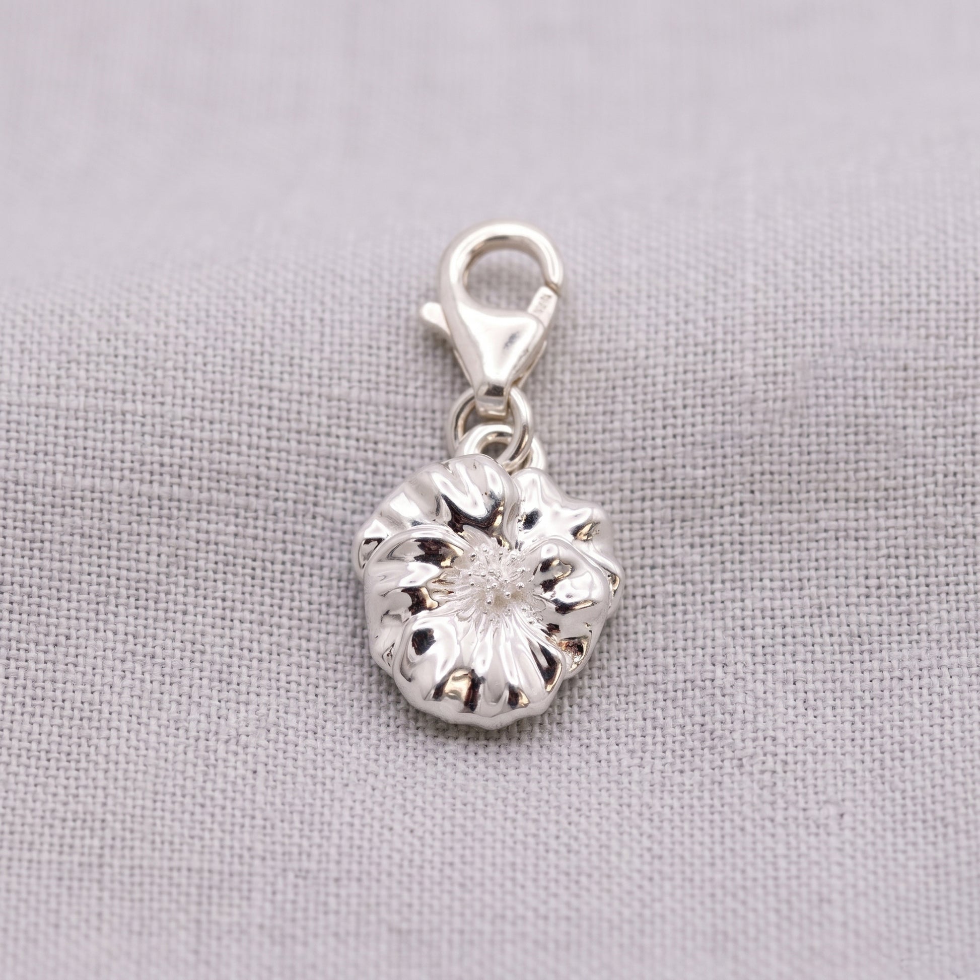Silver violet flower charm on a gray background