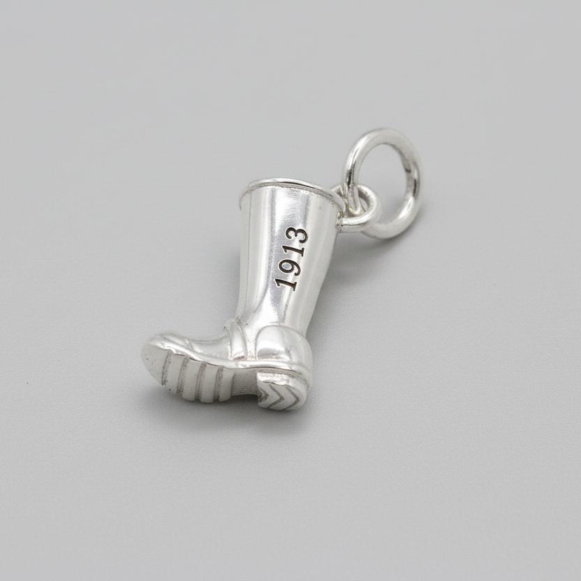 Silver boot charm with '1913' engraving on a gray background
