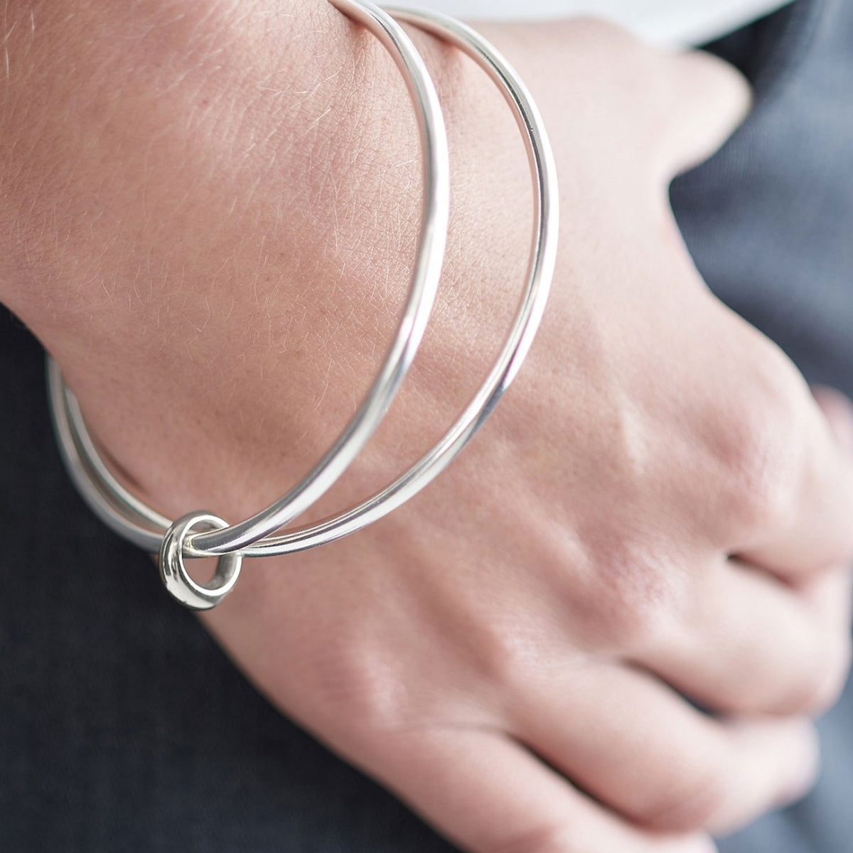 Two solid silver bangles joined in eternity by an asymmetrical Eclipse loop - a gorgeous designer made bangle for women.